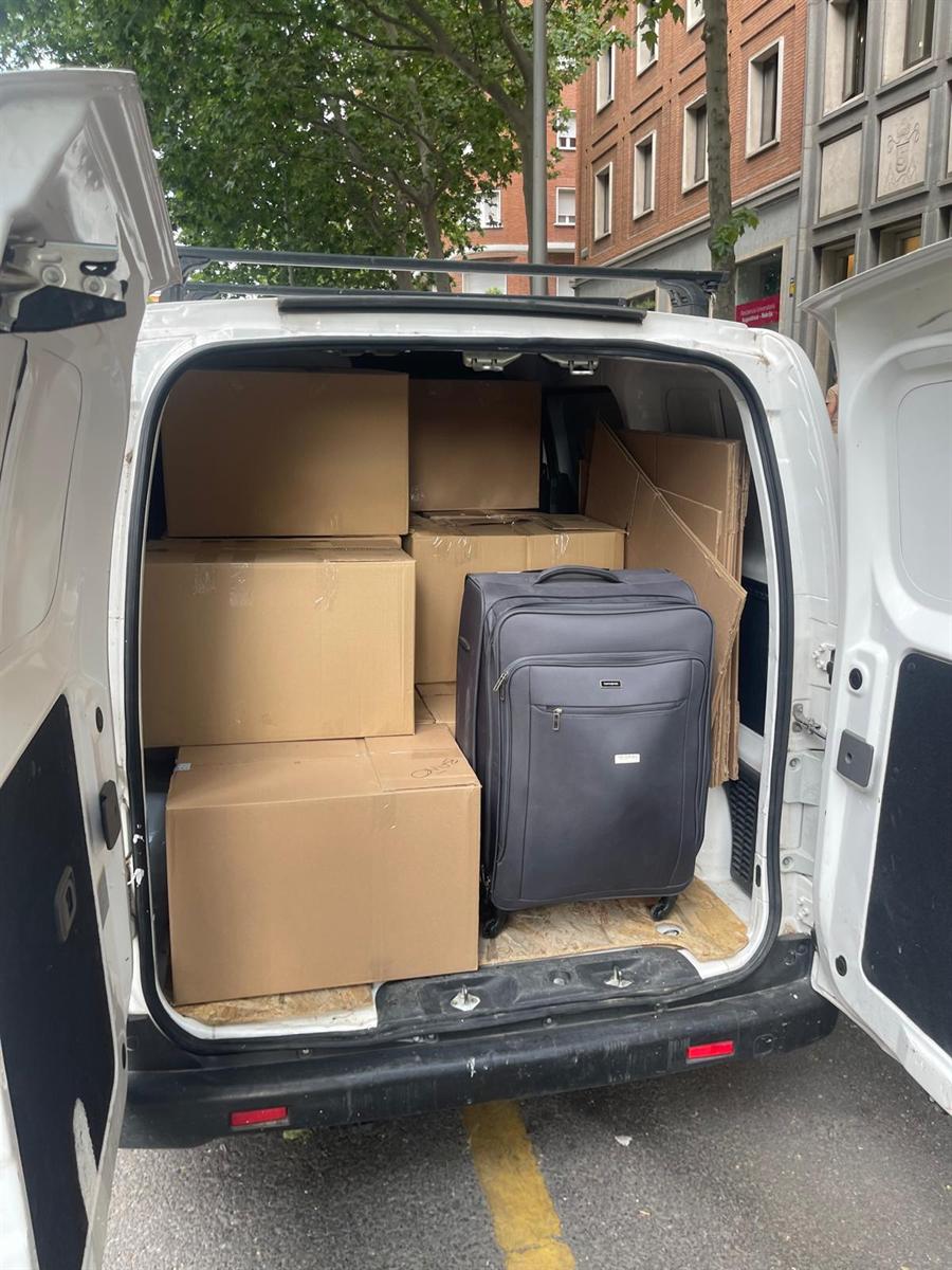 Furgoneta cargada con cajas y una maleta, con las puertas traseras abiertas en una calle de Madrid